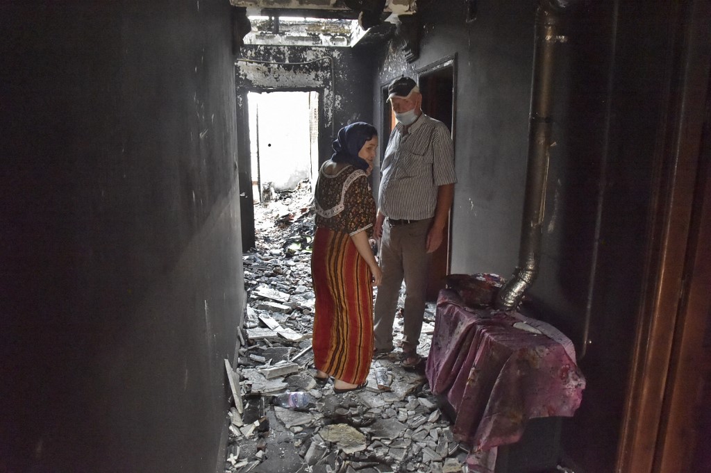 Des Algériens inspectent les dégâts causés à leur domicile par les incendies de forêt dans la région d'Ait Daoud, dans le nord de l'Algérie, le 13 août 2021. (AFP)