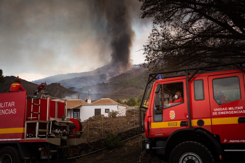 Des pompiers se tiennent à côté de maisons dans le quartier résidentiel de Los Campitos à Los Llanos de Aridane, sur l'île canarienne de La Palma le 20 septembre 2021