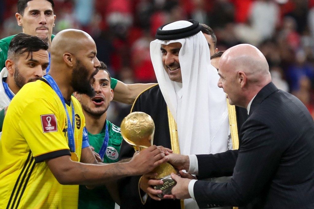 L'émir du Qatar Cheikh Tamim bin Hamad al-Thani (C) et le Président de la FIFA Gianni Infantino (R) présentent le gardien et capitaine de l'Algérie Rais M'Bolhi avec le trophée de la Coupe Arabe de la FIFA 2021 après le dernier match de football entre la Tunisie et l'Algérie à l'Al- Stade Bayt dans la ville qatarie d'Al-Khor, le 18 décembre 2021. (AFP)