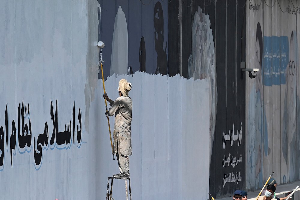 Un homme peint un mur de béton le long d'une rue de Kaboul, le 4 septembre 2021. (Photo, AFP) 