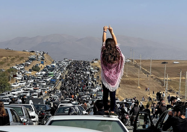 Cette image UGC publiée sur Twitter le 26 octobre 2022 montre une femme non voilée debout sur le toit d'un véhicule alors que des milliers de personnes se dirigent vers le cimetière d'Aichi à Saqez, la ville natale de Mahsa Amini, dans la province du Kurdistan, à l'ouest de l'Iran. (AFP)