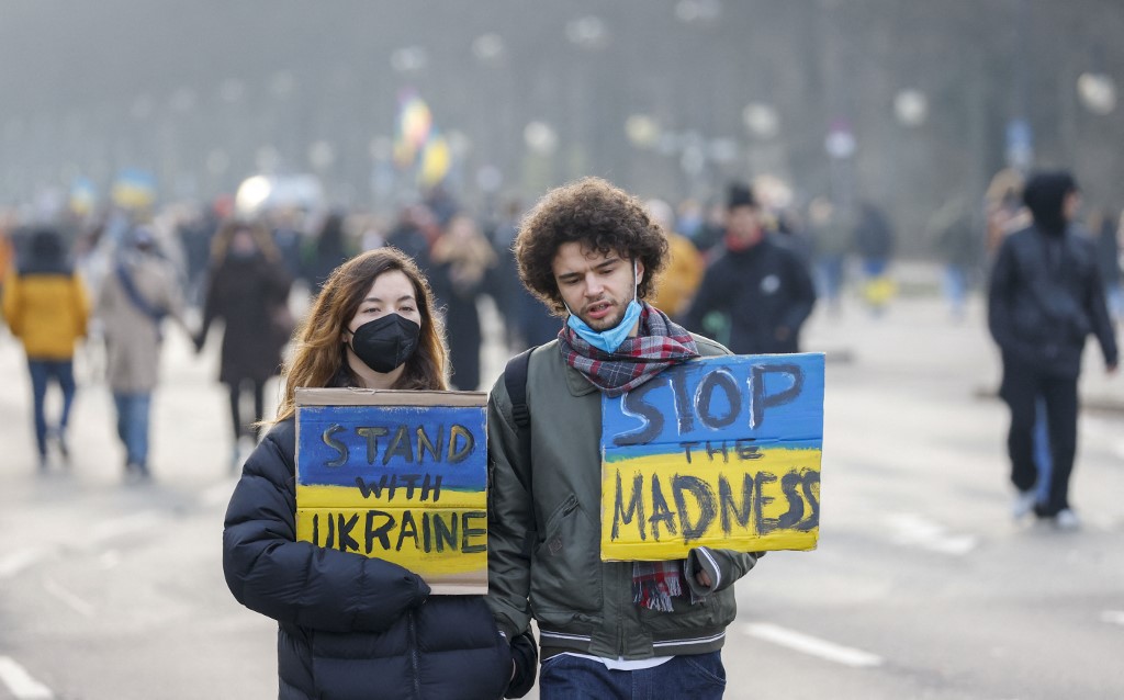 Des manifestants pour la paix en Ukraine portent une pancarte indiquant Stand with Ukraine et Stop the madness à Berlin  e le 27 février 2022