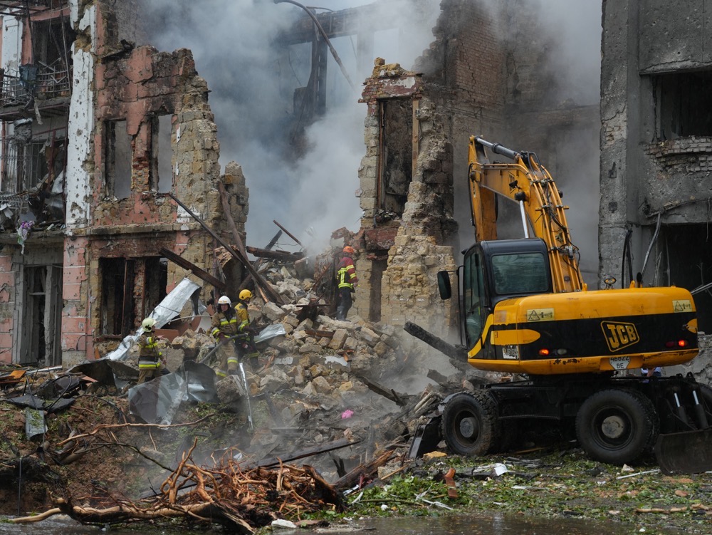 Des secouristes ukrainiens arrosent un bâtiment résidentiel détruit alors qu’ils déplacent des décombres après une frappe de missile à Mykolaiv. (AFP)