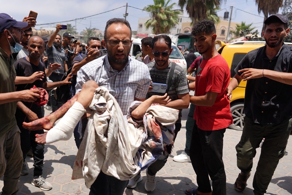 Un homme emmène un enfant blessé à l’hôpital après un bombardement israélien dans le centre de la bande de Gaza. (AFP)