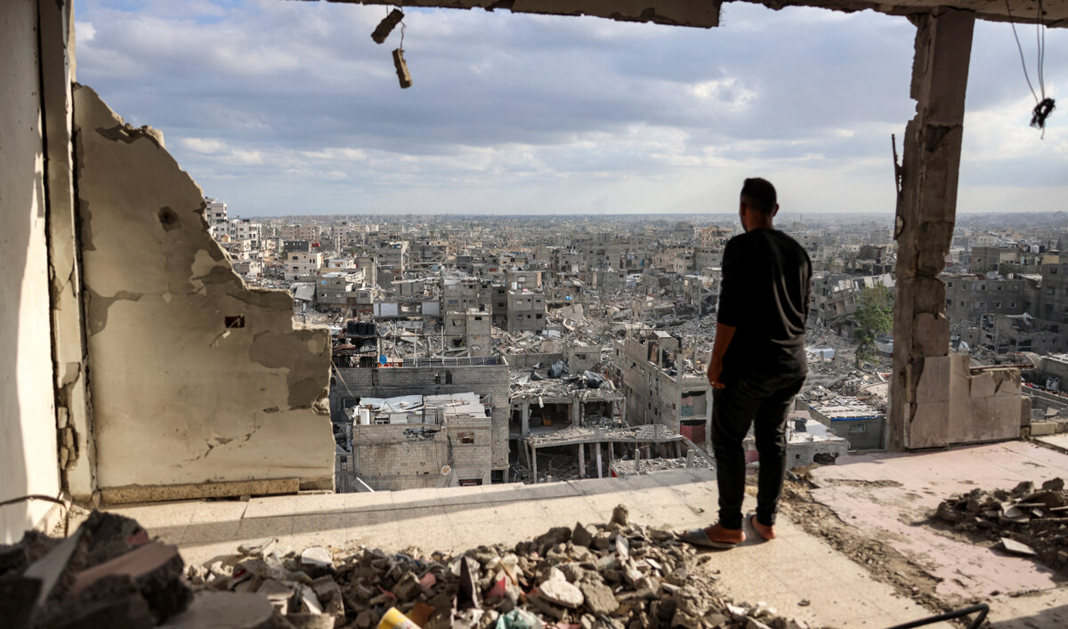 Un homme se tient au sommet d'un bâtiment fortement endommagé et voit d'autres bâtiments détruits à Khan Younès, dans le sud de la bande de Gaza, le 7 octobre 2024. (AFP)