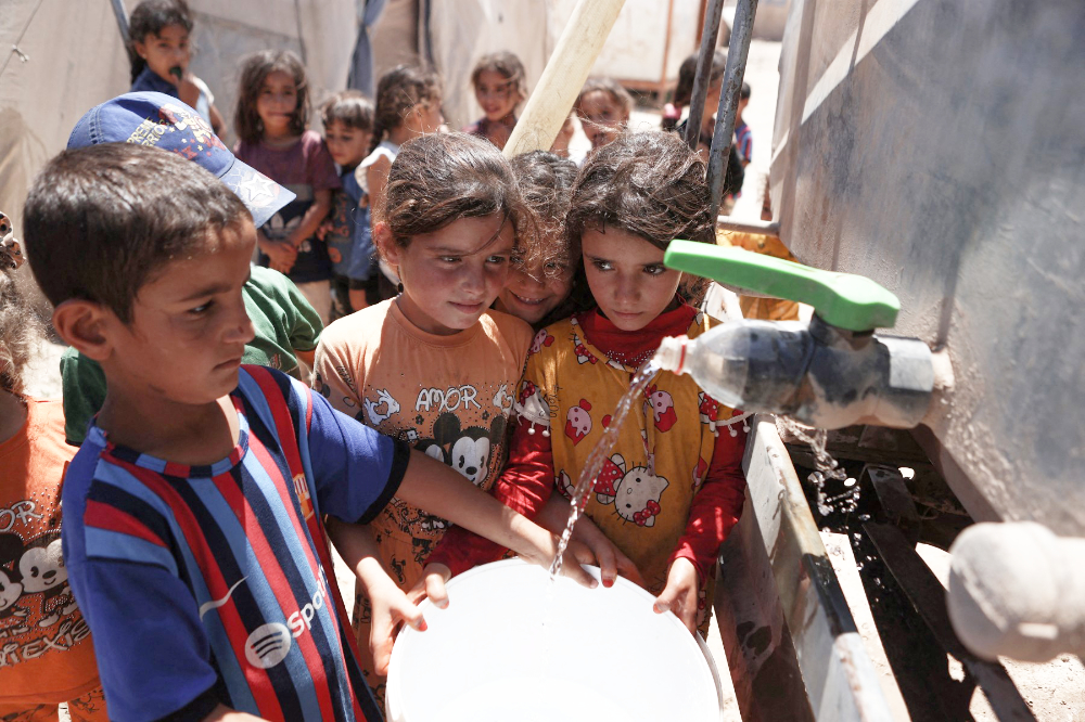 Des enfants syriens remplissent leurs seaux d'eau dans un camp pour personnes déplacées internes près de Sarmada, dans la province syrienne d'Idlib au nord. (AFP)