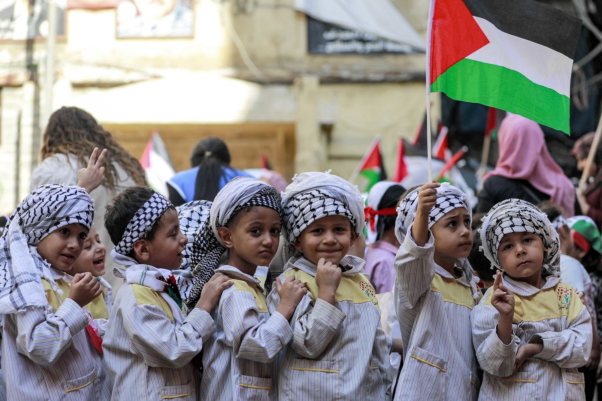 Un écolier tient un drapeau palestinien alors qu’il se tient avec d’autres personnes portant des foulards keffiyeh palestiniens lors d’une manifestation de sit-in au camp de réfugiés palestiniens de Shatila dans la banlieue sud de Beyrouth le 7 novembre 2023. (AFP)