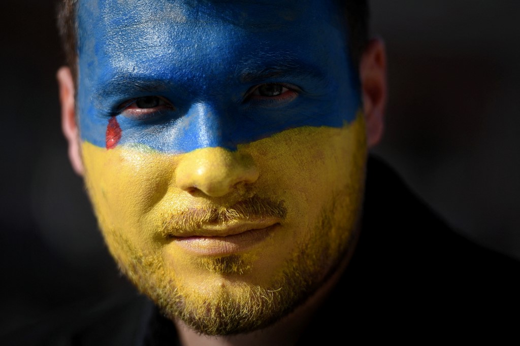 Un manifestant maquillé de bleu et de jaune sur le visage, couleurs du drapeau ukrainien, assiste à une manifestation place du Capitole, à Toulouse, le 27 février 2022.jpg