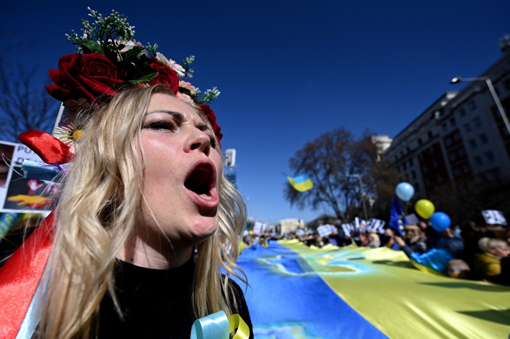 Une manifestante portant une couronne de fleurs traditionnelle ukrainienne Vinok tient un drapeau ukrainien géant lors d'une manifestation contre l'invasion de l'Ukraine par la Russie, à Madrid le 27 février 2022