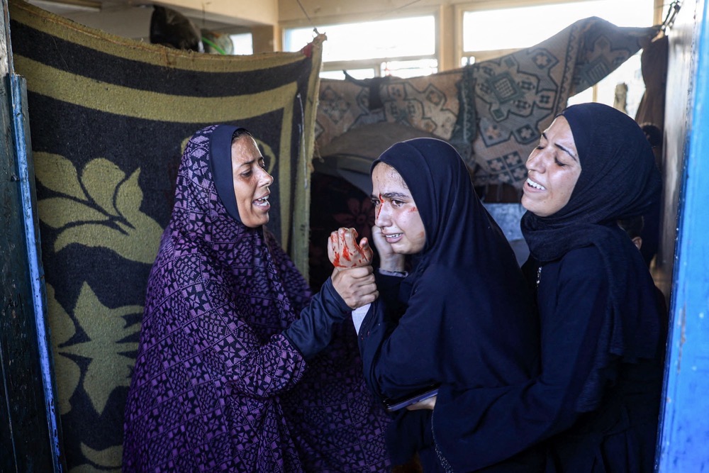 Des femmes réagissent après les bombardements israéliens alors qu'elles se réfugient à l'école de Jaouni. (AFP)