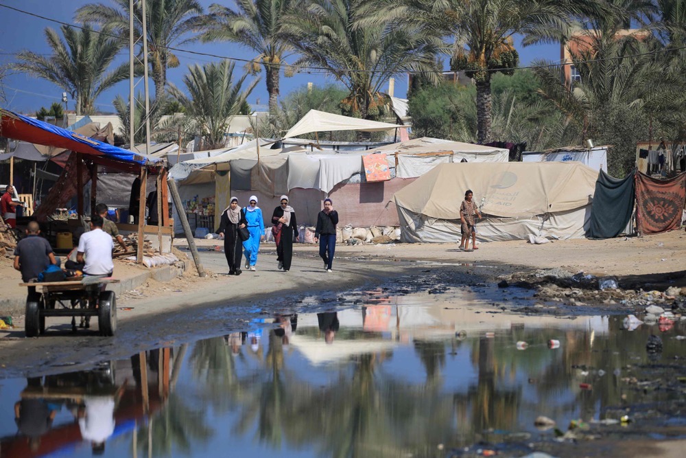 Des palestiniens marchent dans une rue inondée par les eaux usées à Deir El-Balah. (AFP)