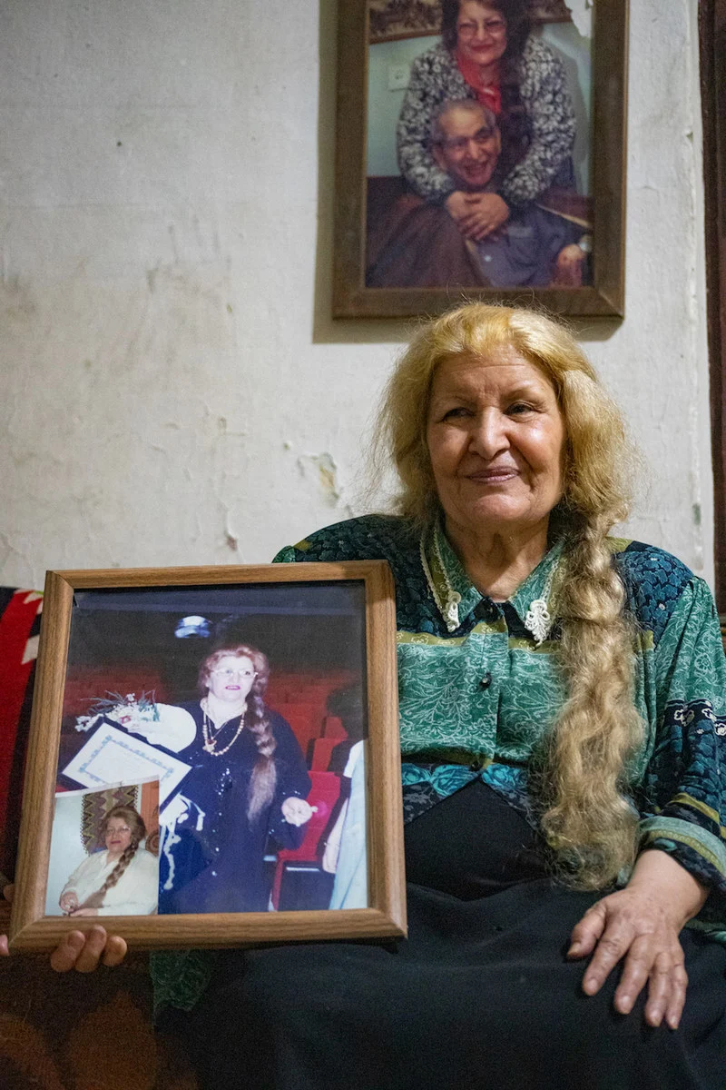 L’écrivaine Fawziya al-Marai, 74 ans, tient une ancienne photo d’elle-même, avec une photo du regretté poète syrien Abdal Salam al-Ujayli en arrière-plan. (Photo AN/Ali Ali)