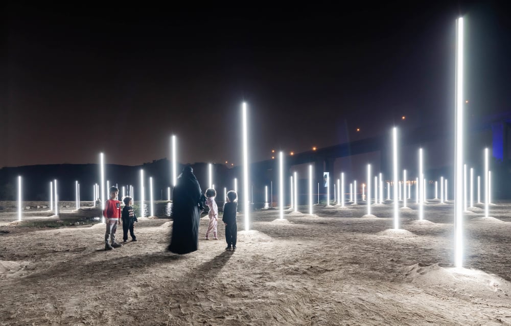Des enfants jouent au football devant One Thousand Galaxies of Light, une œuvre de l’artiste américaine d’origine portoricaine Gisela Colon. Il s’agit d’une configuration elliptique de 100 tubes lumineux blancs verticaux, chacun d’entre eux mesurant 2,5 mètres de haut. (Photo fournie)
