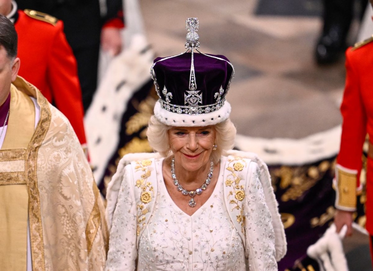 La reine Camilla porte un ensemble blanc, long jusqu’au sol, avec des broderies dorées, conçu par Bruce Oldfield, OBE, un créateur de mode britannique surtout connu pour ses vêtements de fête haute couture. (Getty Images)