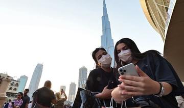 Des femmes portant des masques de protection regardent un téléphone portable devant Burj Khalifa, à Dubaï, le 8 mars 2020 (Photo, AFP) 