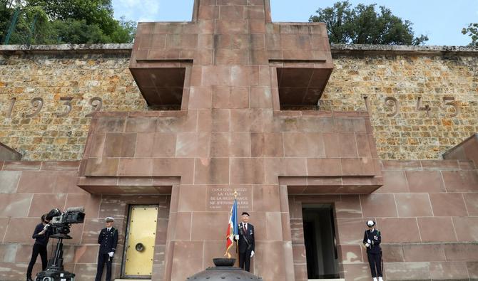 Le vétéran Hugues Goudon de La Lande (C) pose avec le drapeau de la Résistance française devant la Croix de Lorraine et la flamme de la Résistance au Mont-Valérien, un mémorial pour les Français qui ont combattu les nazis et ceux qui ont été tué par les forces d'occupation, à Suresnes, dans l'ouest de Paris, le 18 juin 2020, au début de la traditionnelle cérémonie annuelle. LUDOVIC MARIN / AFP / POOL