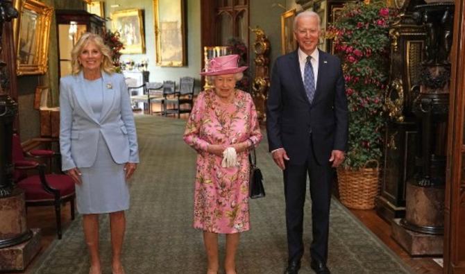 En robe à fleur et chapeau roses, la souveraine de 95 ans, encadrée par Joe Biden et sa femme Jill (Photo, AFP)