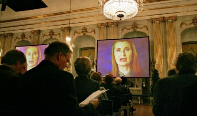 La lauréate du prix Nobel de littérature autrichienne Elfriede Jelinek (à l'écran) apparaît dans une conférence vidéo à l'Académie suédoise de Stockholm le 07 décembre 2004. Jelinek a été la première lauréate de littérature depuis l'Australien Patrick White en 1973 à ne pas venir à Stockholm pour la remise des prix. (Jonas Ekstromer / Scanpix Suède / AFP)