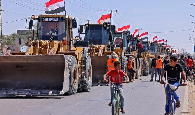 Des garçons palestiniens passent à vélo devant un convoi de bulldozers fournis par l’Égypte, alors qu’ils arrivent du côté palestinien du poste-frontière de Rafah entre l’Égypte et la bande de Gaza, le 4 juin 2021 (Photo, AFP) 