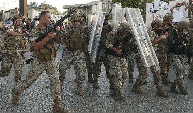 Dans cette photo d'archive du 12 septembre 2020, un soldat de l'armée libanaise, à gauche, tire en l'air pour repousser les manifestants antigouvernementaux alors que d'autres soldats se protègent des pierres, lors d'une manifestation contre le président libanais Michel Aoun près du palais présidentiel , à Baabda à l'est de Beyrouth, au Liban (Fichier/AP