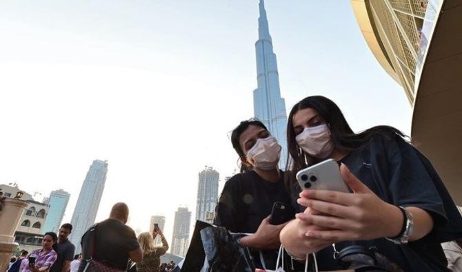 Des femmes portant des masques de protection regardent un téléphone portable devant Burj Khalifa, à Dubaï, le 8 mars 2020 (Photo, AFP) 