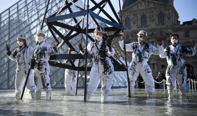 Ces militants, vêtus de combinaison portées sur les plateformes pétrolières, ont dressé un puits de pétrole factice de plusieurs mètres de haut dans une fontaine de l'esplanade du Louvre et installé une banderole avec le slogan «Climat: Total criminel, le Louvre complice» (Photo, AFP)