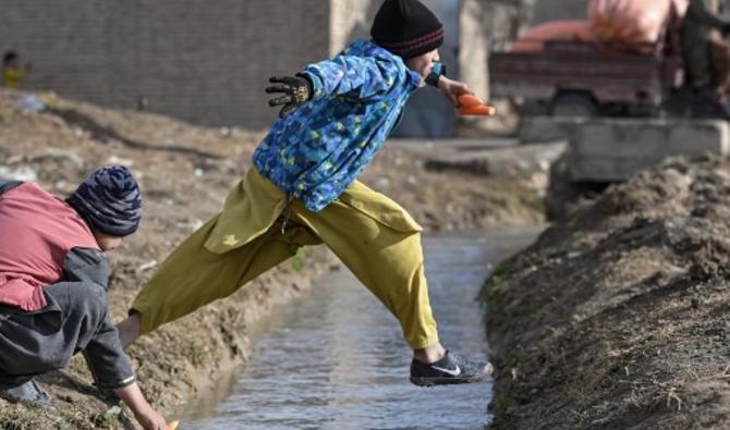 Un enfant saute un fossé en tenant des carottes à Balkh, au nord-ouest de Mazar-i-Sharif, le 22 décembre 2021. (Photo, AFP)