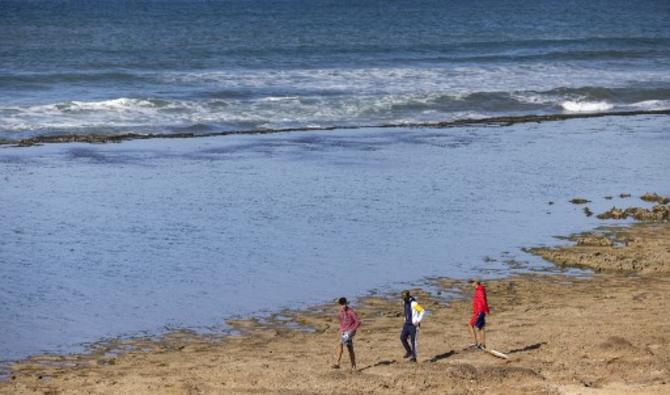 Des Marocains se tiennent au bord de la mer alors qu'ils vérifient la zone où un bateau transportant des migrants marocains a chaviré lors d'une tentative d'atteindre l'Europe par la mer, à Skhirat le 12 novembre 2021. (Photo, AFP)