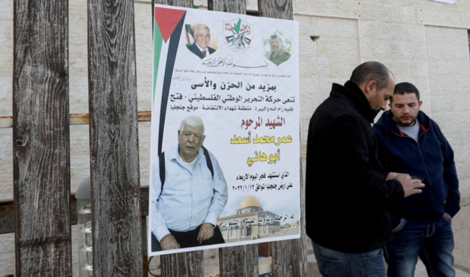 Des hommes se tiennent à côté d'une affiche du Palestinien Omar Abdalmajeed Assad, dans le village de Jiljilya en Cisjordanie occupée par Israël, le 12 janvier 2022. (Reuters)