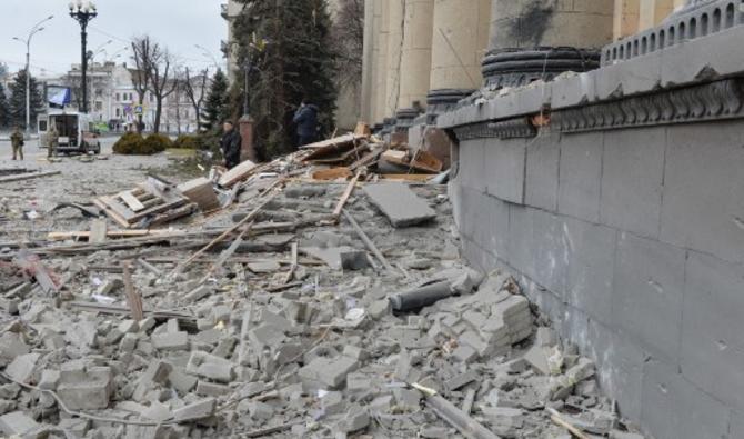 Des hommes armés se tiennent devant l'hôtel de ville local endommagé de Kharkiv, le 1er mars 2022. (Photo, AFP)