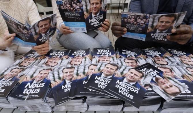 Des partisans politiques du président français et candidat à l'élection présidentielle Emmanuel Macron lisent la brochure du programme politique de leur candidat, à Paris, le 19 mars 2022. (Photo, AFP)