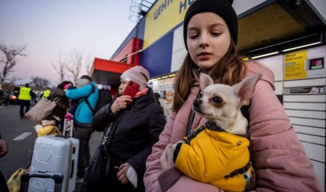 Une fille tient son chien alors qu'elle et d'autres réfugiés ukrainiens attendent d'être transportés au centre d'enregistrement de Przemysl, dans le sud-est de la Pologne, le 19 mars 2022. (Photo, AFP)