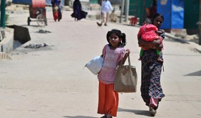 Des Rohingyas marchent dans une rue après avoir collecté du matériel de secours dans le camp de réfugiés de Jamtoli à Ukhia, le 22 mars 2022. (Photo, AFP)