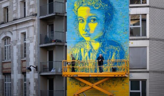 Le street artiste et peintre français Christian Guemy devant sa fresque, à Paris, le 10 mars 2022. (Photo, AFP)