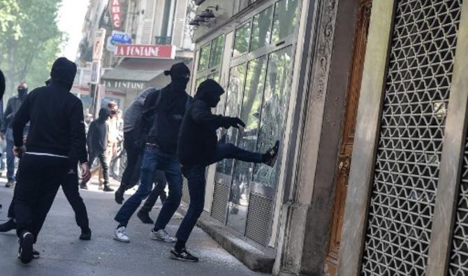 Un manifestant donne un coup de pied dans la vitrine d'une entreprise en marge du rassemblement annuel du 1er mai (fête du travail), à Paris le 1er mai 2022. (Photo, AFP)