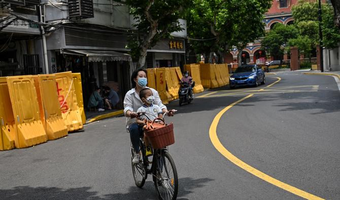 Une femme fait du vélo dans une rue du quartier Jing'an de Shanghai le 2 juin 2022, suite à l'assouplissement des restrictions de Covid-19 dans la ville après un confinement de deux mois. (Photo, AFP)