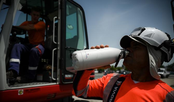 Un ouvrier boit de l'eau sur un chantier de construction lors d'une chaude journée à Mérignac, près de Bordeaux, dans le sud-ouest de la France, le 14 juin 2022. (Photo, AFP)