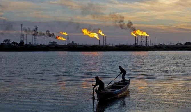 Des pêcheurs irakiens dans leur bateau devant des feux issus du champ pétrolifère de Nahr ben Omar, au nord du port de Bassorah. (Fichier/AFP)