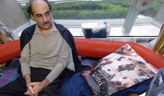 Dans cette photo d'archive prise le 12 août 2004 Mehran Karimi Nasseri regarde une affiche du film inspiré de sa vie, dans le terminal 1 de l'aéroport Paris Charles De Gaulle. (Photo, AFP)