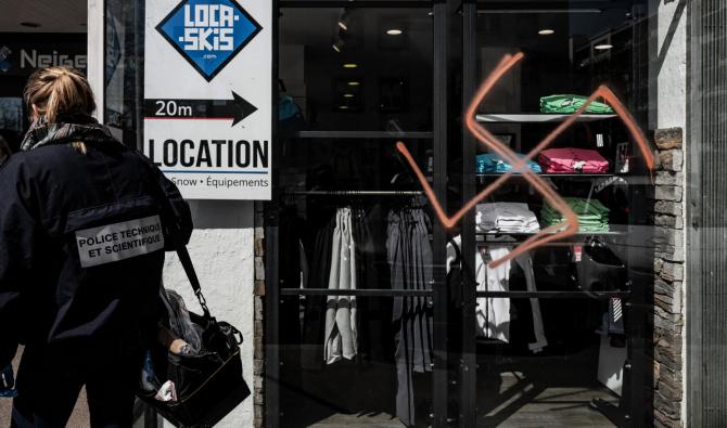 Un policier judiciaire enquête sur une croix gammée peinte à la bombe sur la vitrine d'un magasin de Lyon, le 5 avril 2019 (Photo, AFP).