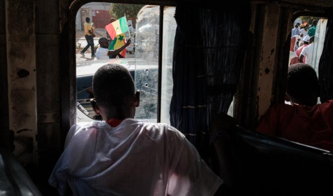 Des enfants regardent à travers les vitres d'un bus les partisans de l'actuel président du Sénégal se rassembler pour soutenir leur leader à Dakar, le 24 février 2024. (Photo, AFP)