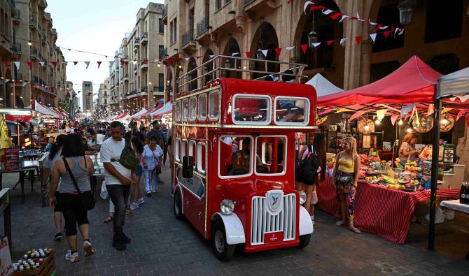 Un véhicule habillé comme un bus à deux étages roule près des participants au festival de la rue de Beyrouth, dans le centre-ville de Beyrouth, le 22 juin 2024. (Photo par Joseph EID / AFP)